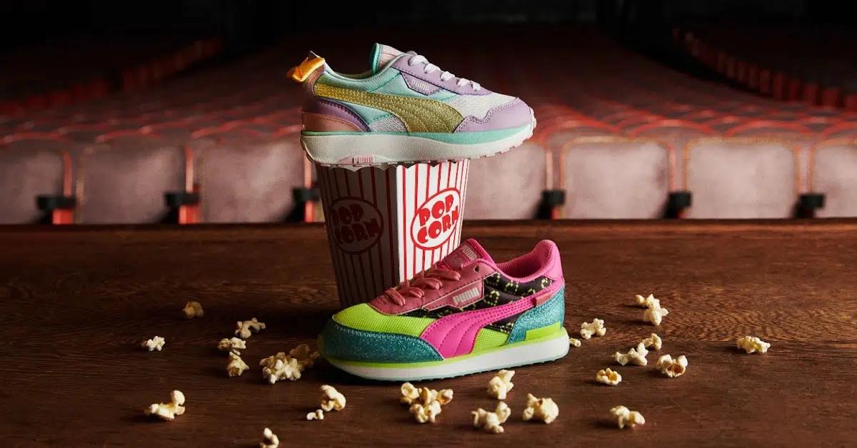 LOL Surprise themed sneakers displayed on a theatre stage with empty seats in the background and popcorn spilled on the stage in the foreground. One shoe is on top of a popcorn bucket.